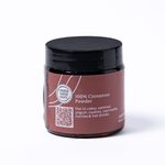 Jar of cinnamon powder with a black lid on a white background