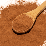 Wooden spoon with cocoa powder on a surface of cocoa powder
