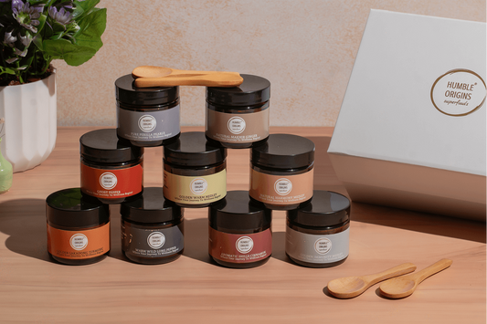 Complete Wellness Collection of nine spice jars with wooden spoons beside a white Humble Origins gift box