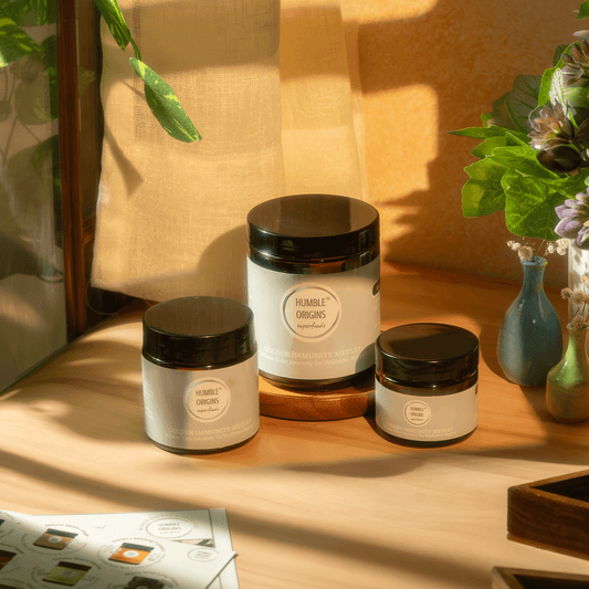 Three jars with black lids on a wooden surface, with a warm light casting shadows.