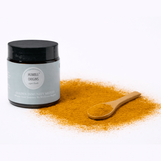 Jar of 'Humble Origins' golden immunity mix with a wooden spoon on a white background