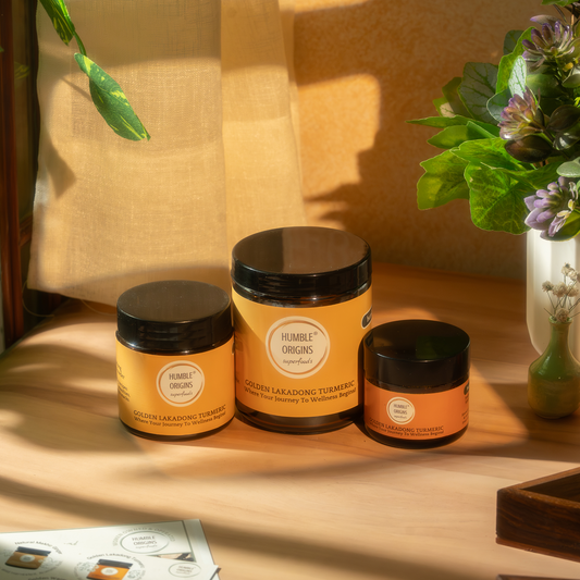 Three jars of 'Humble Origins' on a wooden surface with a soft, warm light.