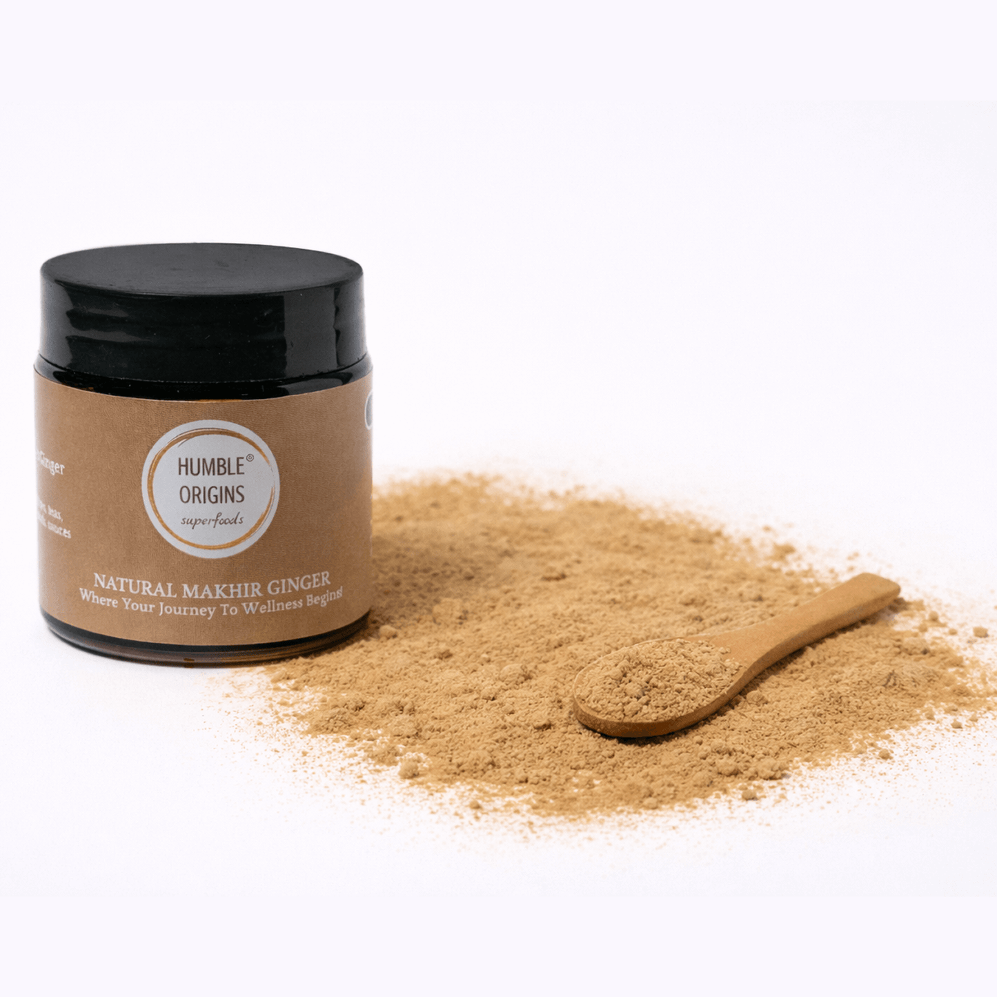 Jar of Humble Origins Makhir Ginger powder with a wooden spoon on a white background
