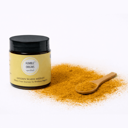 Jar of 'Humble Origins Golden Warm Medley' with a wooden spoon on a white background