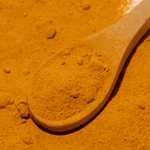 Spoonful of orange powder on a bed of orange powder