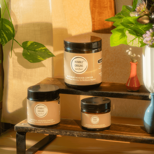 Three jars of 'Humble Origins' product on a wooden surface with a warm, natural light setting.