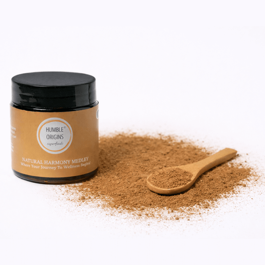 Jar of 'Humble Origins' natural product with a wooden spoon filled with powder on a white background