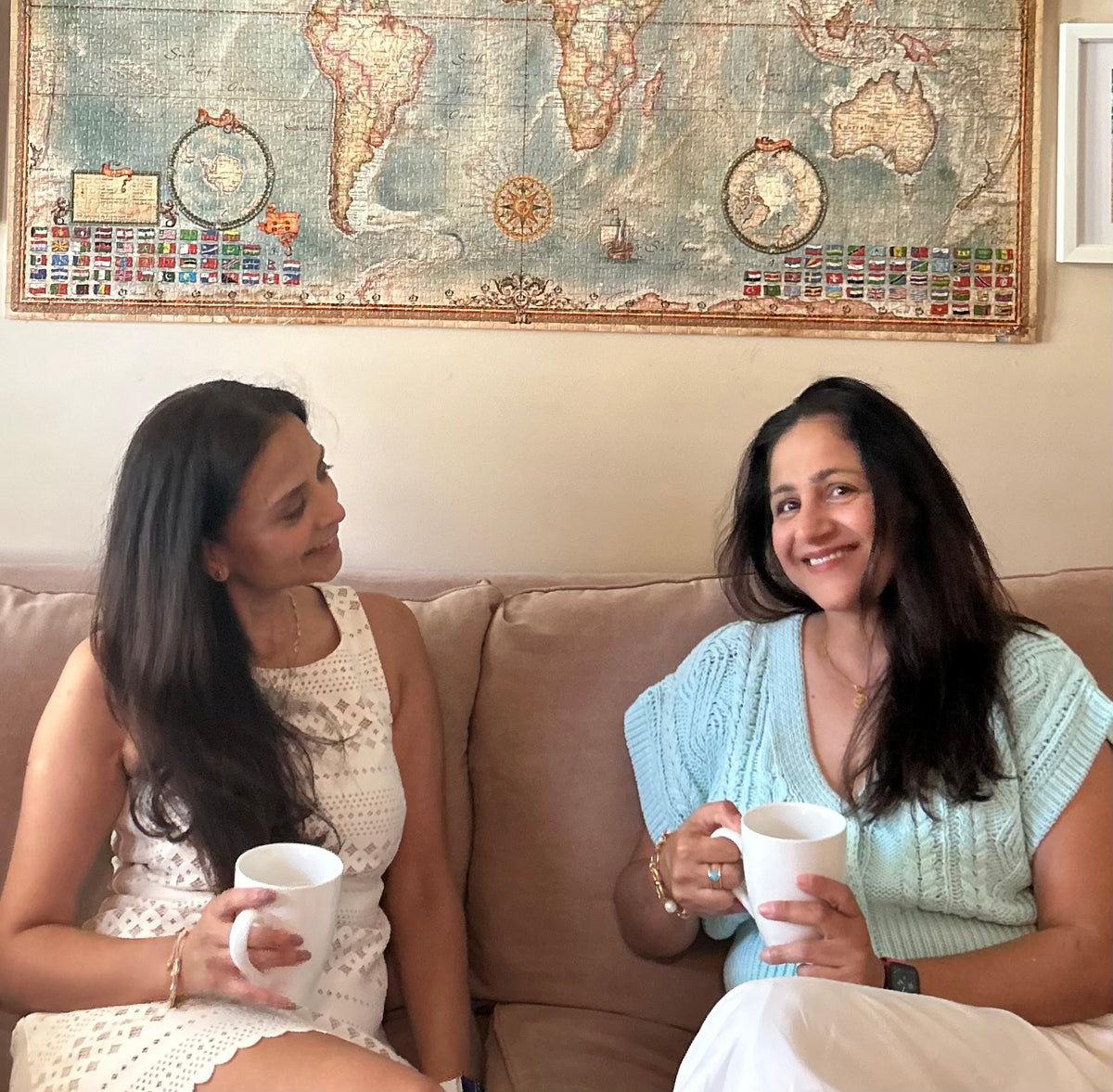 Ushma and Malvika on a couch with mugs of Golden Immunity Medley golden milk